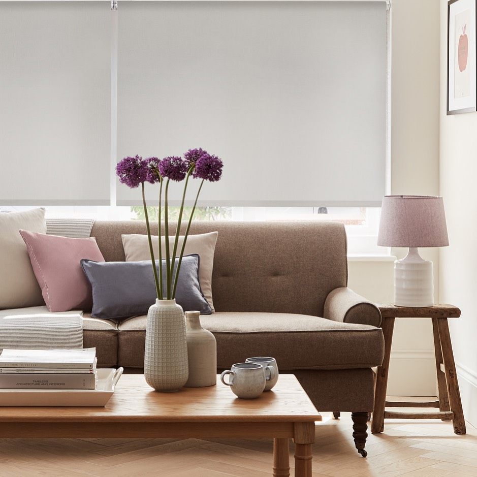 Grey made-to-measure roller blinds fitted in a neutral living room